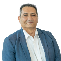 Professional head-and-shoulders portrait of a man in a blue blazer and white shirt, looking at the camera against a white background.