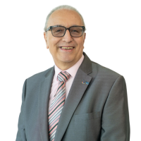 Smiling older man in a gray suit with a pink striped tie, posing for a professional headshot against a white background.