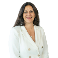 Professional headshot: smiling woman in a white blazer, posing against a light background