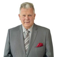 Portrait of a middle-aged man in a gray suit with a striped tie and pink pocket square, looking at the camera.